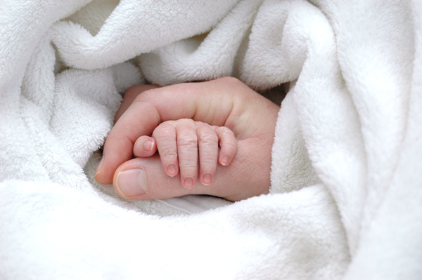 Hand der Mutter hält Babyhand
